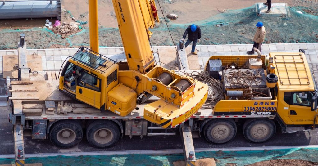 Aerial shot of a construction site showcasing a yellow crane and workers in action.