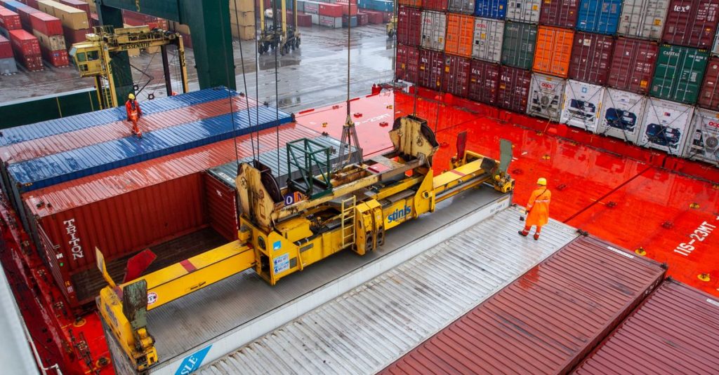 Aerial view of workers managing cargo loading at a bustling port with vibrant shipping containers.