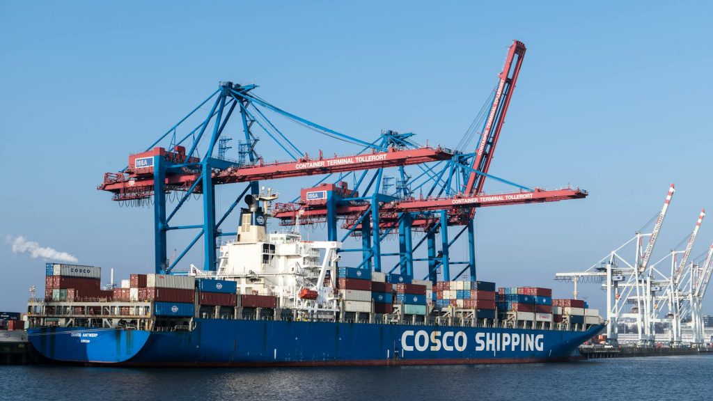Cargo ship at Hamburg port terminal with cranes and containers, showcasing global commerce.