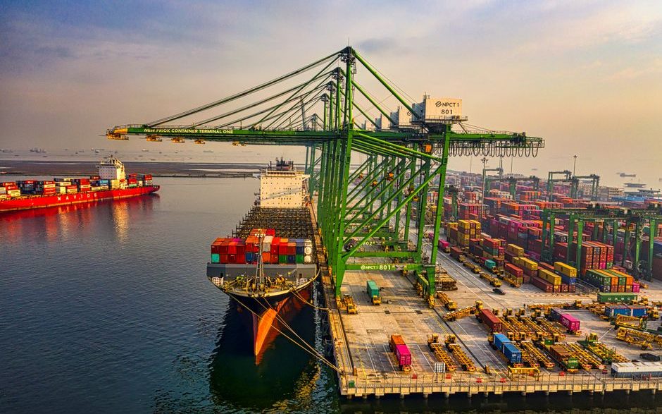 A bustling aerial view of a container port in North Jakarta, Indonesia with ships and cranes.